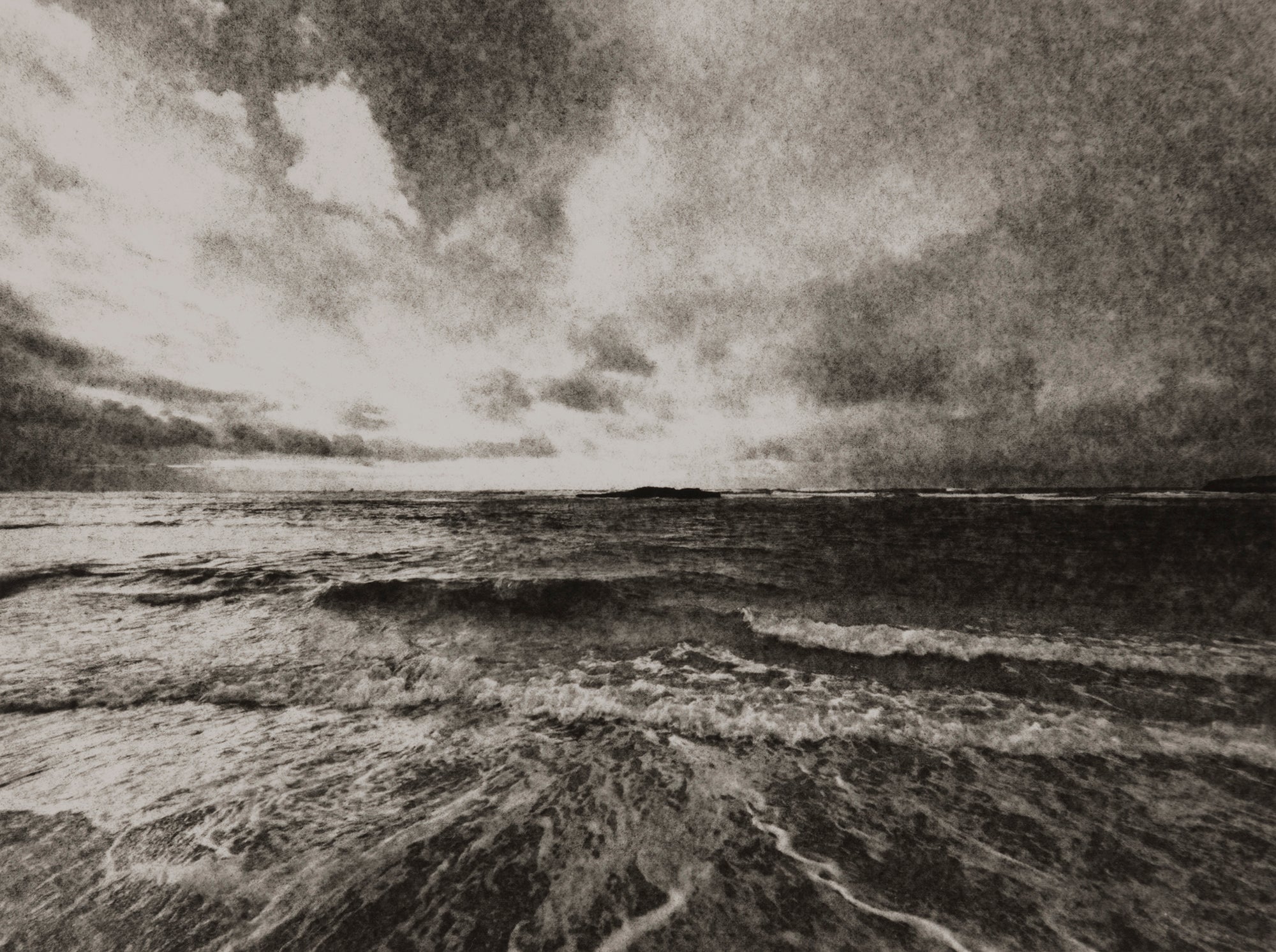 A dramatic coastal shoreline with stormy clouds reflected in the shoreline